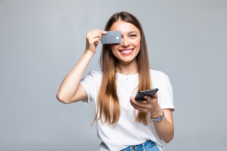 cheerful-excited-young-woman-with-mobile-phone-and-credit-card-min