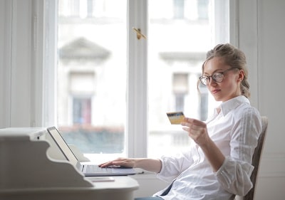 closeup-shot-of-pretty-female-with-white-shirt-working-with-laptop-and-looking-at-her-card-min