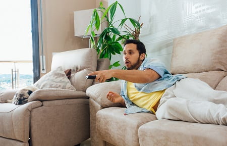 photo-of-handsome-hispanic-man-lying-on-sofa-and-watching-tv-min