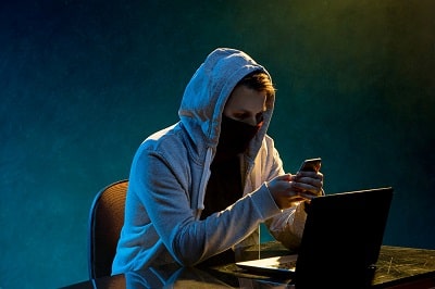 hooded-computer-hacker-stealing-information-with-laptop-min