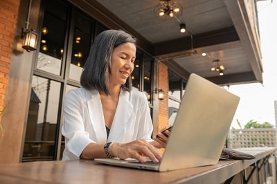 portrait-of-businesswoman-in-cafe-using-laptop-and-mobile-phone-min